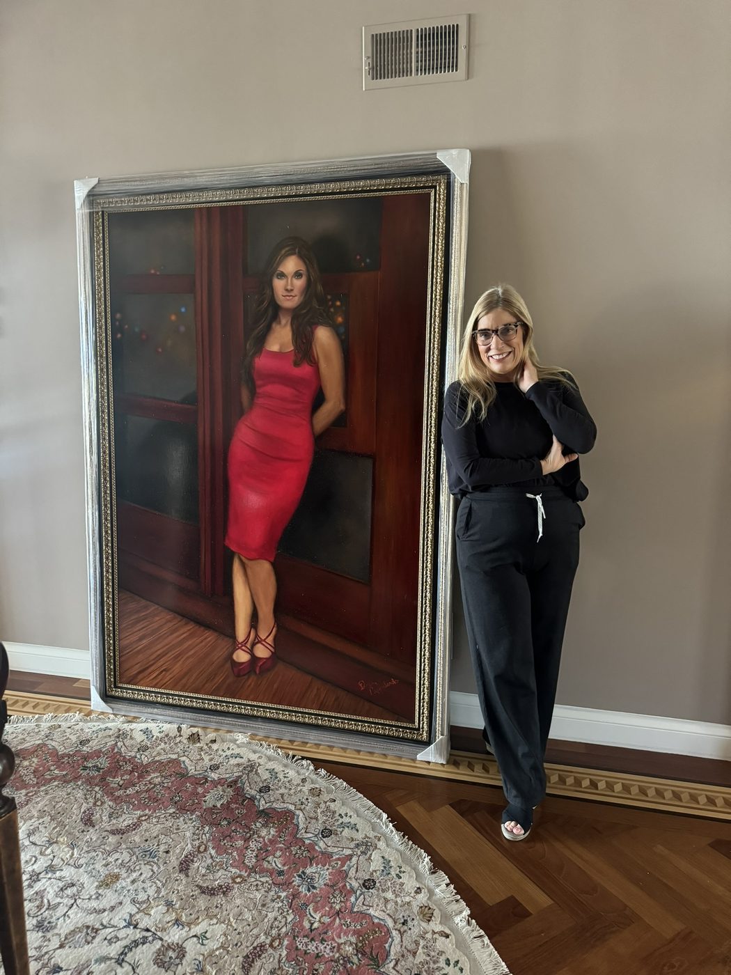 Dayna standing beside the framed red-dress portrait